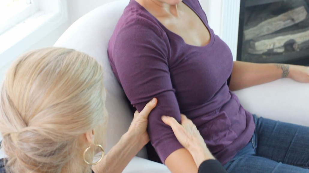 Christine gives an arm massage to a woman in a purple shirt